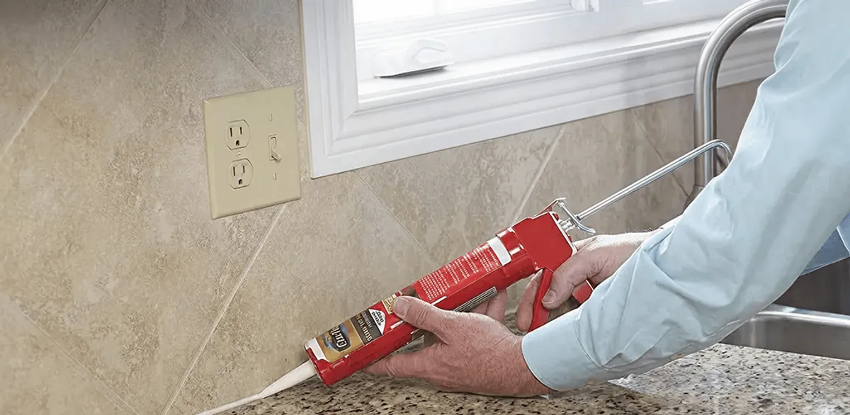 Handyman applying caulk along a kitchen backsplash and countertop seam in Pasadena, CA