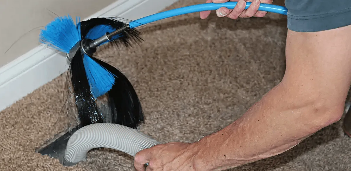 Dryer vent cleaning technician brushing lint from a vent line in Pasadena, CA